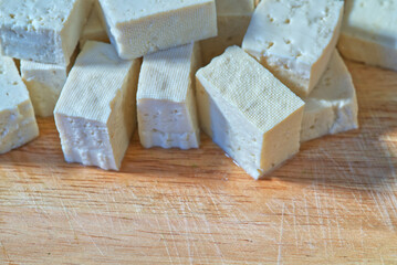Close-up of a group of tofu dice on a wooden cutting board. Landscape image of tofu dice on a cutting board with space. Macro fresh tofu.