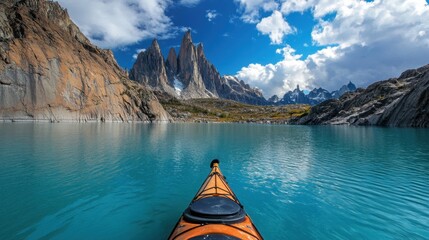 A lone kayak floating on a turquoise alpine lake surrounded by jagged peaks.