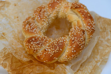 Freshly baked sesame bread ring resting on delicate parchment paper, showcasing golden hues and inviting texture