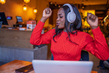 Freelancer enjoying music with headphones while working on laptop in cafe