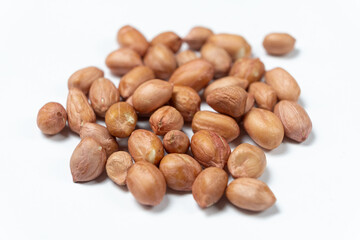 Raw peanut kernels in brown peel on white background macro