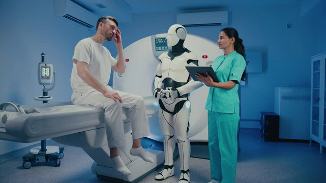 Caucasian male patient sitting on hospital bed and talking during medical consultation. Female doctor in turquoise uniform showing results on tablet while humanoid robot observing silently.