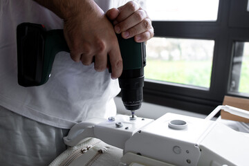 Male using electric drill for home improvement project by window