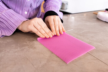 Female crafting beeswax candle with pink sheet on marble table