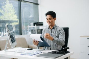 Fototapeta premium Confident businessman working on finance analysis with a tablet and laptop at office desk.
