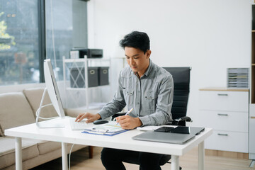 Obraz premium Confident businessman working on finance analysis with a tablet and laptop at office desk.
