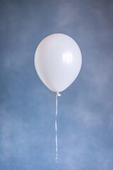 Fototapeta premium Minimalist scene featuring single white balloon against soft blu