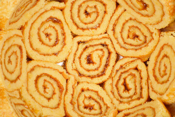 A close-up, top-down view of a bowl filled with jam-filled Swiss roll slices, showcasing their spiral pattern and golden-brown edges