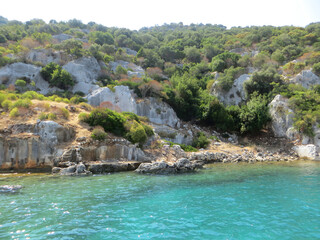 Rocky Mediterranean landscape with dense natural vegetation and rock formations descending to the...