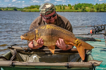 Carpfishing session at the Lake.lucky fisherman holding a giant common carp.Angler with a big carp...