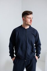 A Casual Fashion Portrait Featuring a Young Man Dressed in a Dark ZipUp Hoodie Set Against a Minimalist Background, Capturing the Essence of Modern Style and Youthful Urban Lifestyle