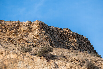Rugged desert hilltop featuring rocky terrain against clear blue sky