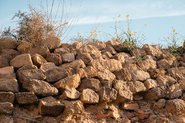 Rustic rock wall with wildflowers under blue sky