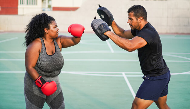 Curvy african american girl and her personal trainer doing sport workout session outdoor - Sport, diet and healthy lifestyle concept - Main focus on faces