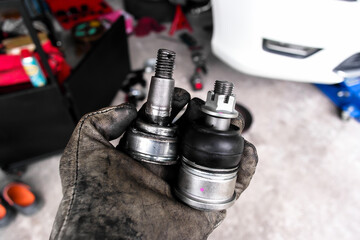 Car ball joints comparison new and old , Automotive repair concept. Hand holding two car ball joints for a vehicle suspension. Indoor shot of garage.