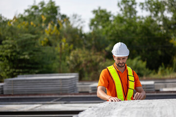 Male civil engineer is using tablet or smart phone conducting a quality check in a precast factory....