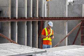 Male civil engineer is using tablet or smart phone conducting a quality check in a precast factory....