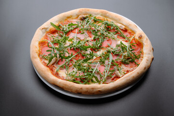 Delicious pepperoni pizza topped with fresh arugula on a dark background