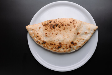 Delicious Calzone on a White Plate Against a Black Background