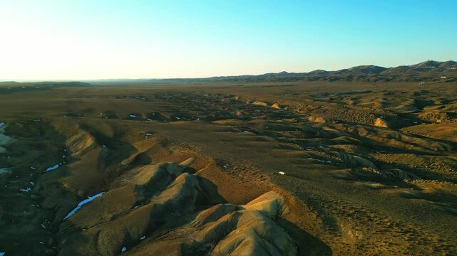 white car drives on narrow dirt road between hills with huge stones and boulders evening sunset nature mangystau