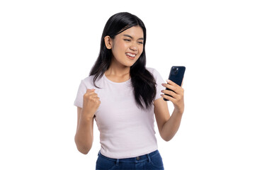 Fototapeta premium Young Asian woman celebrating success while looking at her phone and making a victory gesture, isolated on transparent background