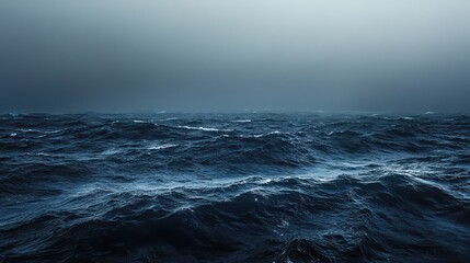 Fototapeta premium vast expanse of stormy ocean, endless waves rolling toward desolate shore, thick fog drifting acrossscene, deep navy and charcoal tones dominatingimage,