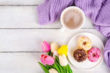 Small sugar glazed donuts with coffee latte cup, tulip flowers, sweater, tulip flower bouquet and note Good Morning. Spring holiday, Mother Day, Woman day, Birthday greeting card background 