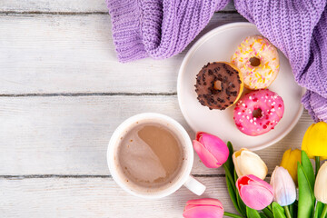 Small sugar glazed donuts with coffee latte cup, tulip flowers, sweater, tulip flower bouquet and note Good Morning. Spring holiday, Mother Day, Woman day, Birthday greeting card background 