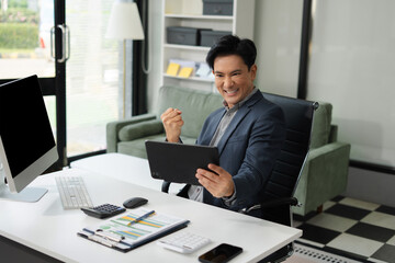 Fototapeta premium Excited man work distant on Tablet talk on cellphone celebrate online win. Happy young male use Tablet feel euphoric overjoyed triumph with good news over Tablet call.