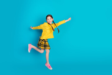 Happy pretty Girl in a Fashionable Outfit Jumping Joyfully Against a Vibrant Blue Background Depicting a Cheerful and Energetic Lifestyle