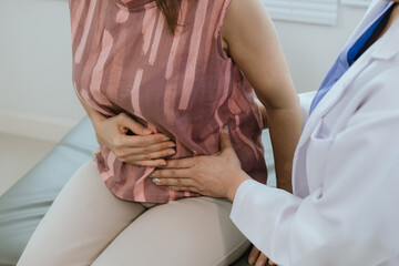 A female doctor examines an elderly woman with abdominal pain. A patient with stomach problems such...