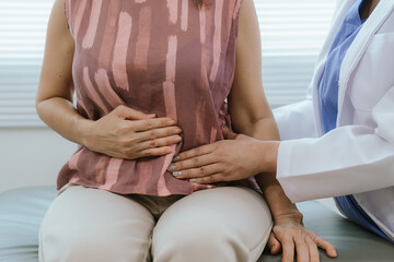 A female doctor examines an elderly woman with abdominal pain. A patient with stomach problems such...