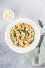 Traditional Italian potato gnocchi with butter, sage, parmesan cheese on a gray background. Top view. Italian cuisine.