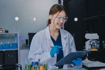 Team Asian scientists in a lab conducting food research using a microscope and lab equipment,...