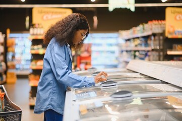 African American woman in grocery store near refrigerator