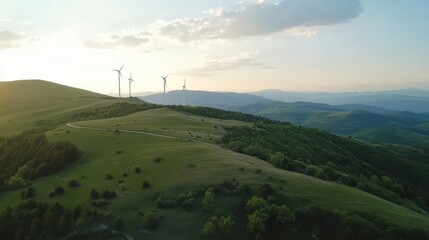 Obraz premium Aerial view of wind turbines on green hills at sunset, a landscape with a mountain range and blue sky