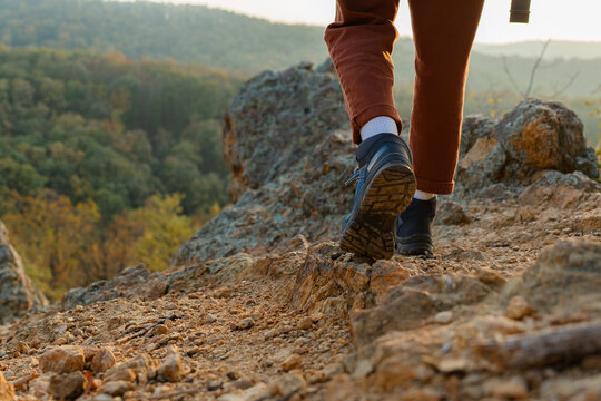 Photographer hiking along a rocky mountain path, soaking in the stunning sunset landscape and vibrant autumn colors
