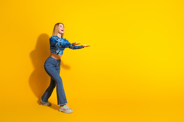 Fashionable young woman posing with enthusiasm against vibrant yellow background showcasing casual style and cheerful demeanor