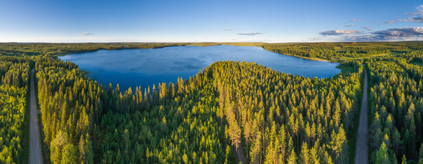 Aerial view in panorama format over boreal forest with lake in central Finland
