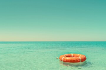 Bright orange flotation ring drifting on tranquil turquoise waters during a sunny day at the beach