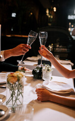 Toasting glasses during a romantic dinner in a dimly lit restaurant setting