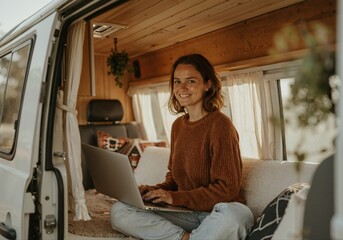 Young woman working remotely from her laptop inside a cozy camper van, enjoying the freedom of a digital nomad lifestyle