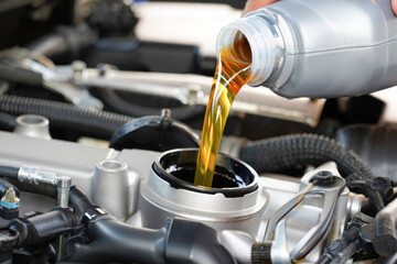 Pouring fresh motor oil into car engine for optimal performance and longevity