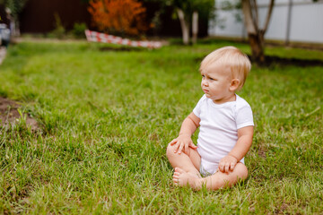Happy Smiling Baby Sitting on Green Grass Outdoors
