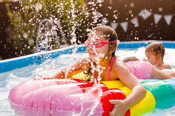 Smiling kid having fun in pool on colorful inflatable toy at summer day