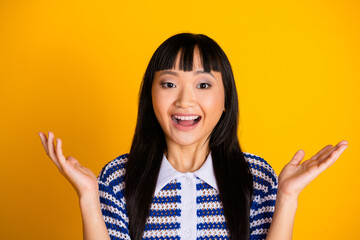 Cheerful Young Woman Gesturing Enthusiastically in a Stylish Outfit Against Vibrant Yellow...