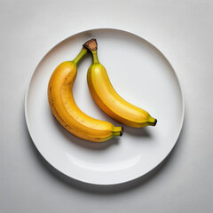 Ripe yellow bananas on a white plate on a white background. Top view.