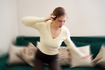 Young woman gets dizzy, loses her balance in the living room. Tired girl with closed eyes having...