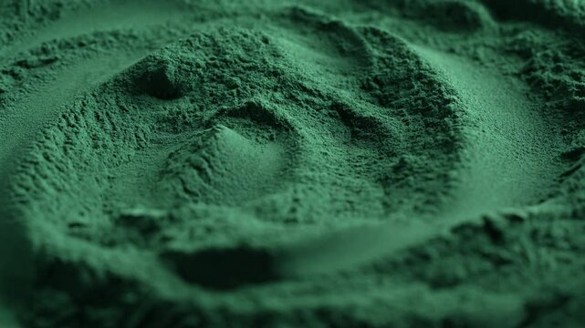 Heap of green spirulina algae powder spins, close up. Green powder super food, macro, rotation. Dietary supplement to improve health. Seaweed superfood concept. Healthy food background