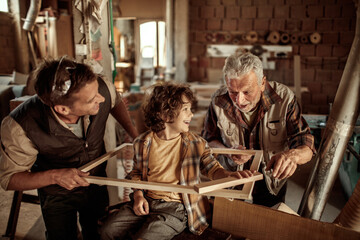 Three generations of men bonding in woodworking workshop